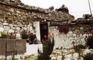 Alte Griechin sitzt vor ihrem Steinhaus im Dorf von Siana.
